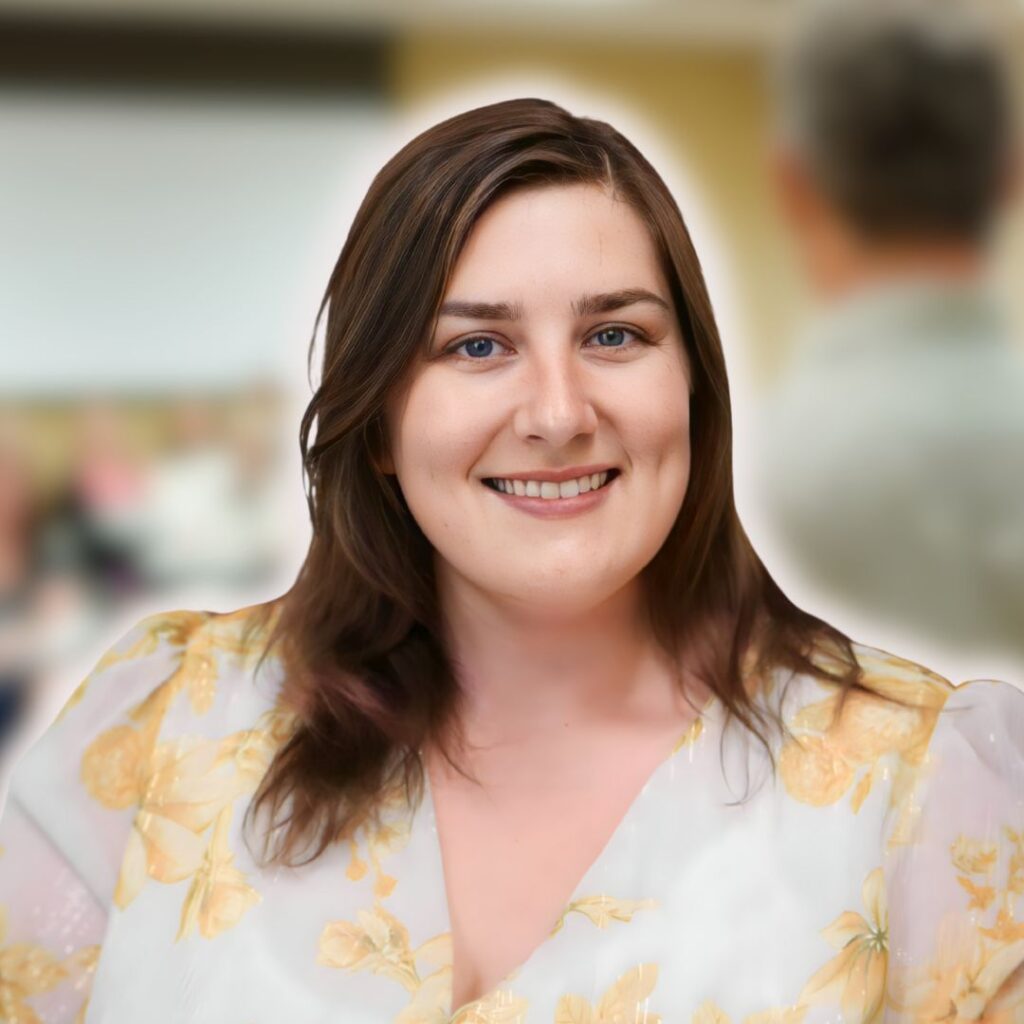 Smiling woman with long brown hair in a floral blouse, representing personalized coaching and mentorship for intuitive growth and business strategy.