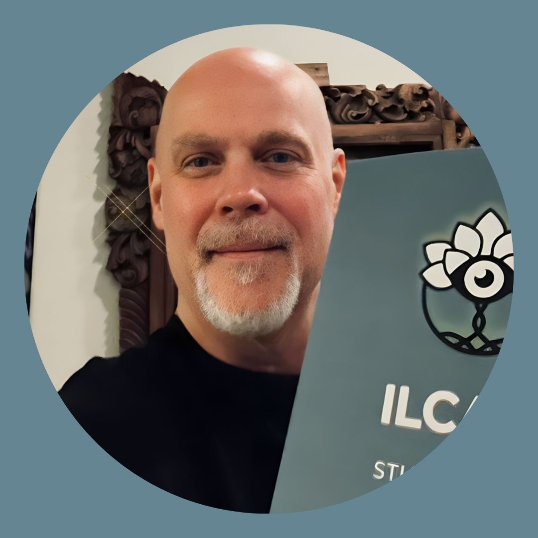 Man smiling and holding an ILCATE sign, representing the Intuitive Life Coaching Academy of Training & Excellence community and personalized coaching.